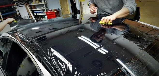 Lepenie čiernej lesklej fólie Lepenie čiernej lesklej fólie na strechu s použitím vody na povrchu fólie proti poškrabaniu.